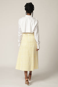 Back view of model with braids wearing a white shirt and yellow and white striped skirt