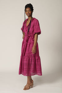 Model with braids poses in a fuchsia lace midi wrap dress with tie at waist