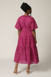 Back view of a model with braids wearing a fuchsia lace midi wrap dress with tie at waist