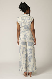 Back view of a model with braids wearing a cropped sleeveless blue and white printed jacket and matching wide leg pant