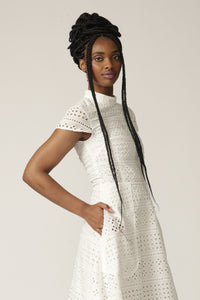 Close up of a model with braids wearing a white capped-sleeve lace dress