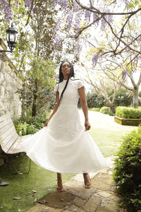 model with braids wearing white lace dress poses in a garden