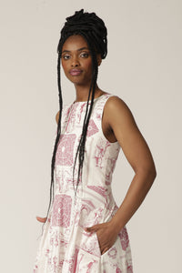 Close up of a model with braids wearing a boat-neck white midi dress with a red print and pocket detail