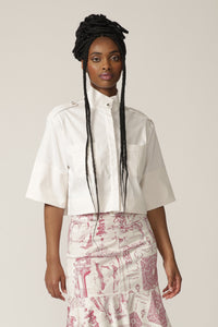 Model with braids wears a white cropped jacket with high neck
