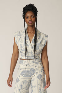 Model with braids wears a sleeveless white and blue printed jacket with matching pants