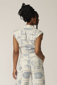 Back view of a model with braids wearing a sleeveless white and blue printed jacket with matching pants