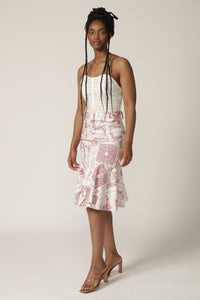 Model with braids wears a white lace corset and a red printed skirt with ruffle hem