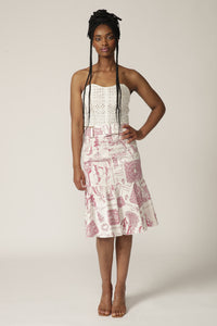 Model with braids poses in a white lace corset and a red printed skirt with ruffle hem